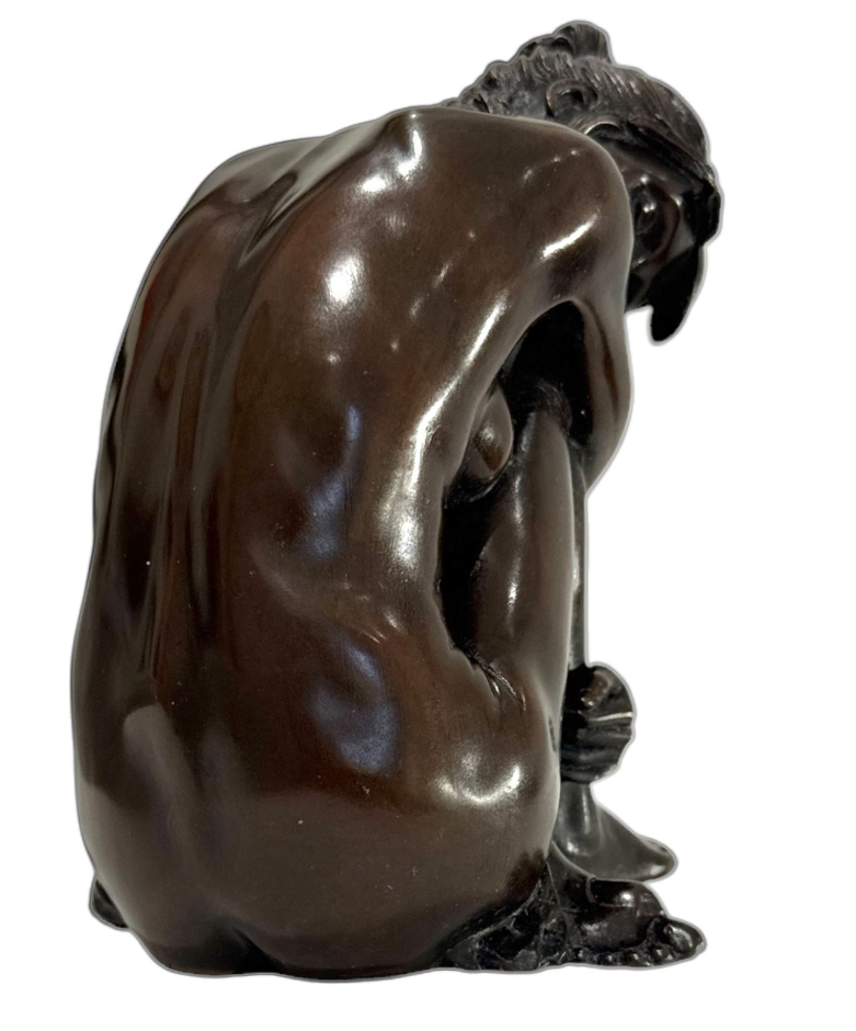 Bronze sculpture of a figure with a flowing garment on a white background