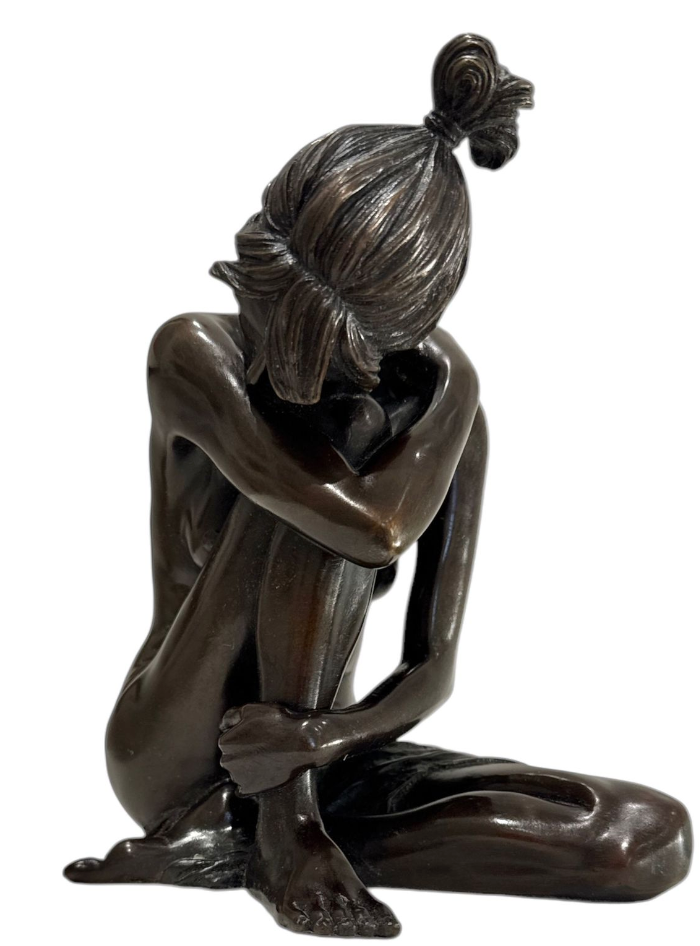 Bronze sculpture of a seated figure with a bun on a white background