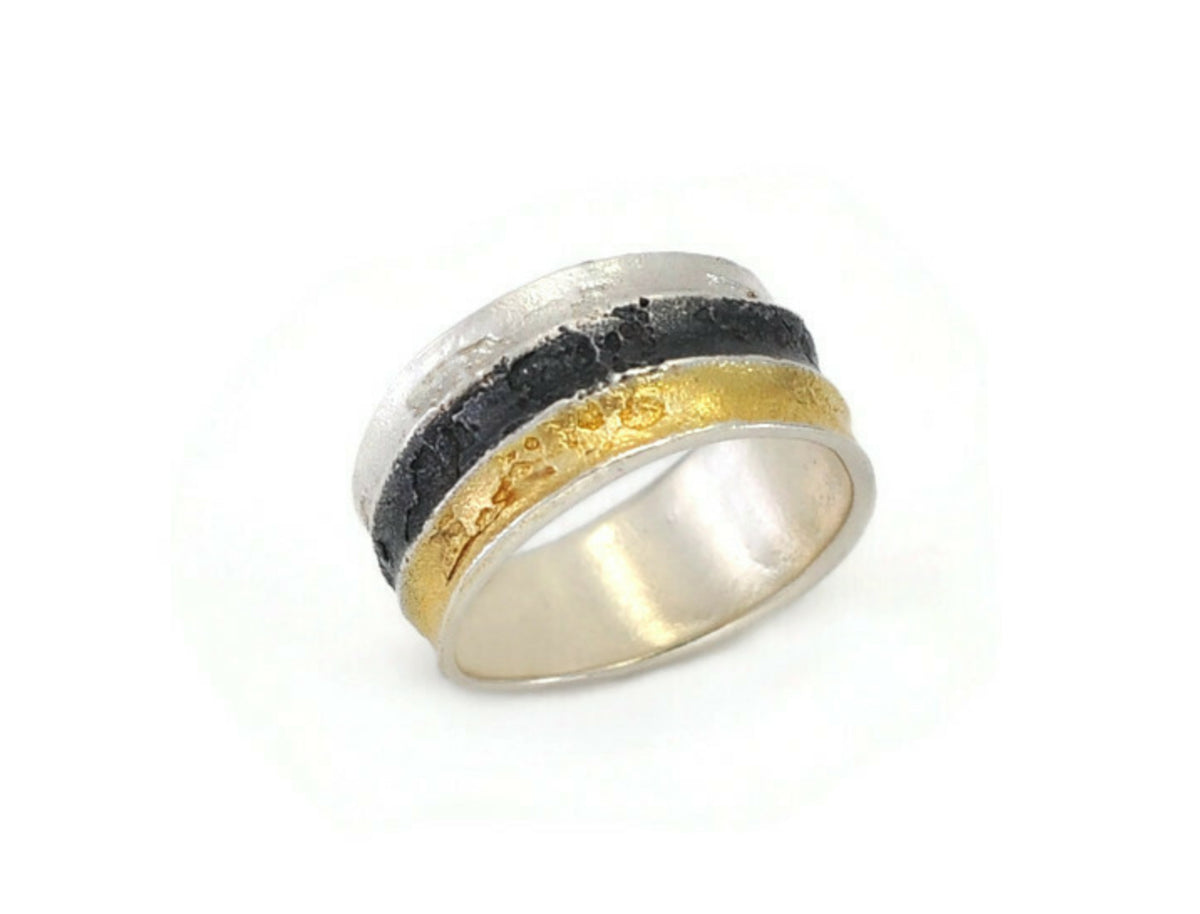 Silver ring with gold and black band on a white background