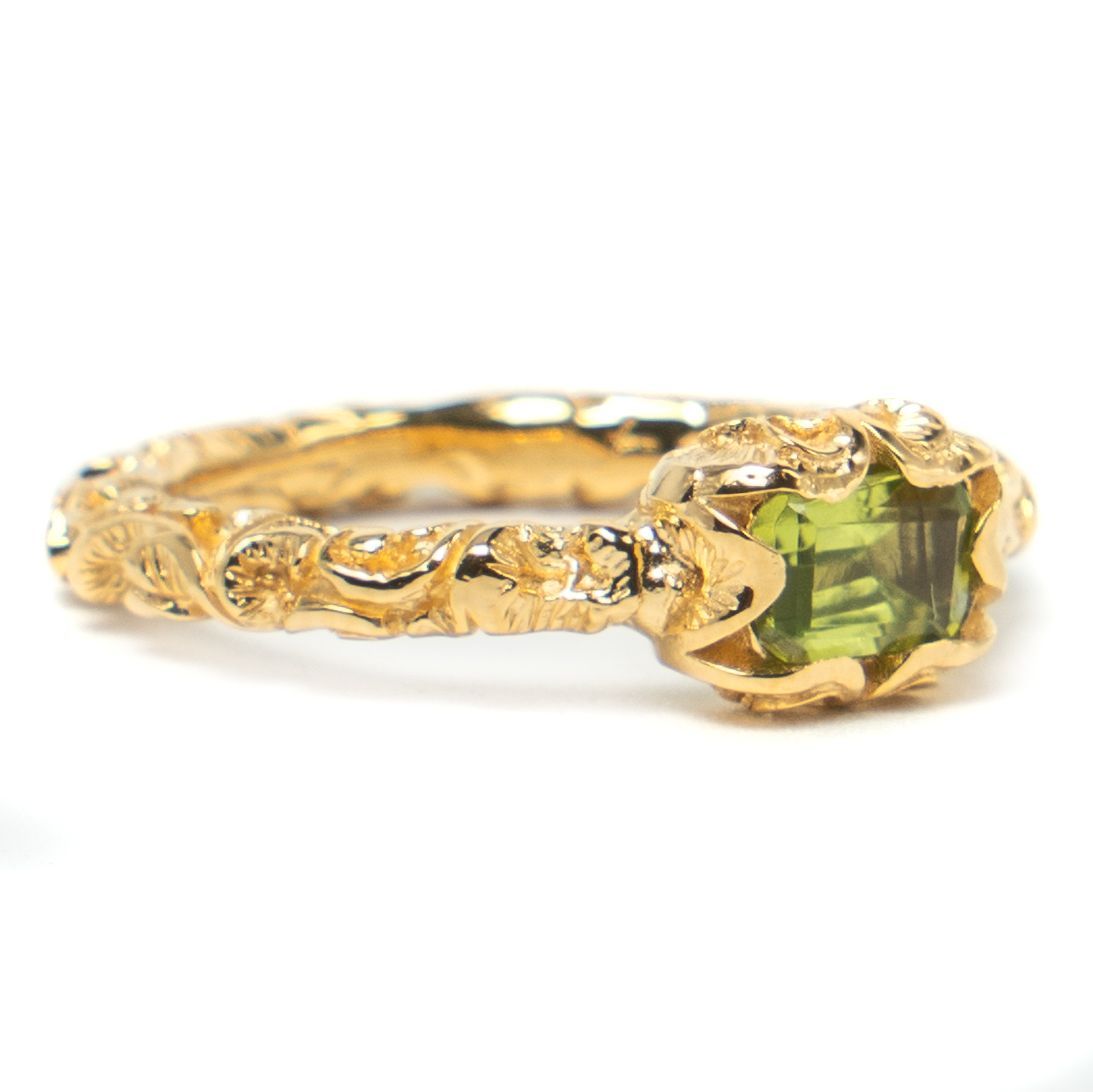 Gold ring with a green gemstone on a white background