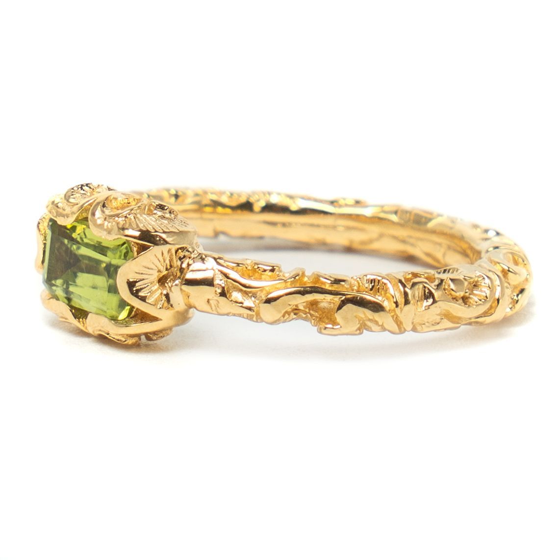 Gold ring with a green gemstone on a white background