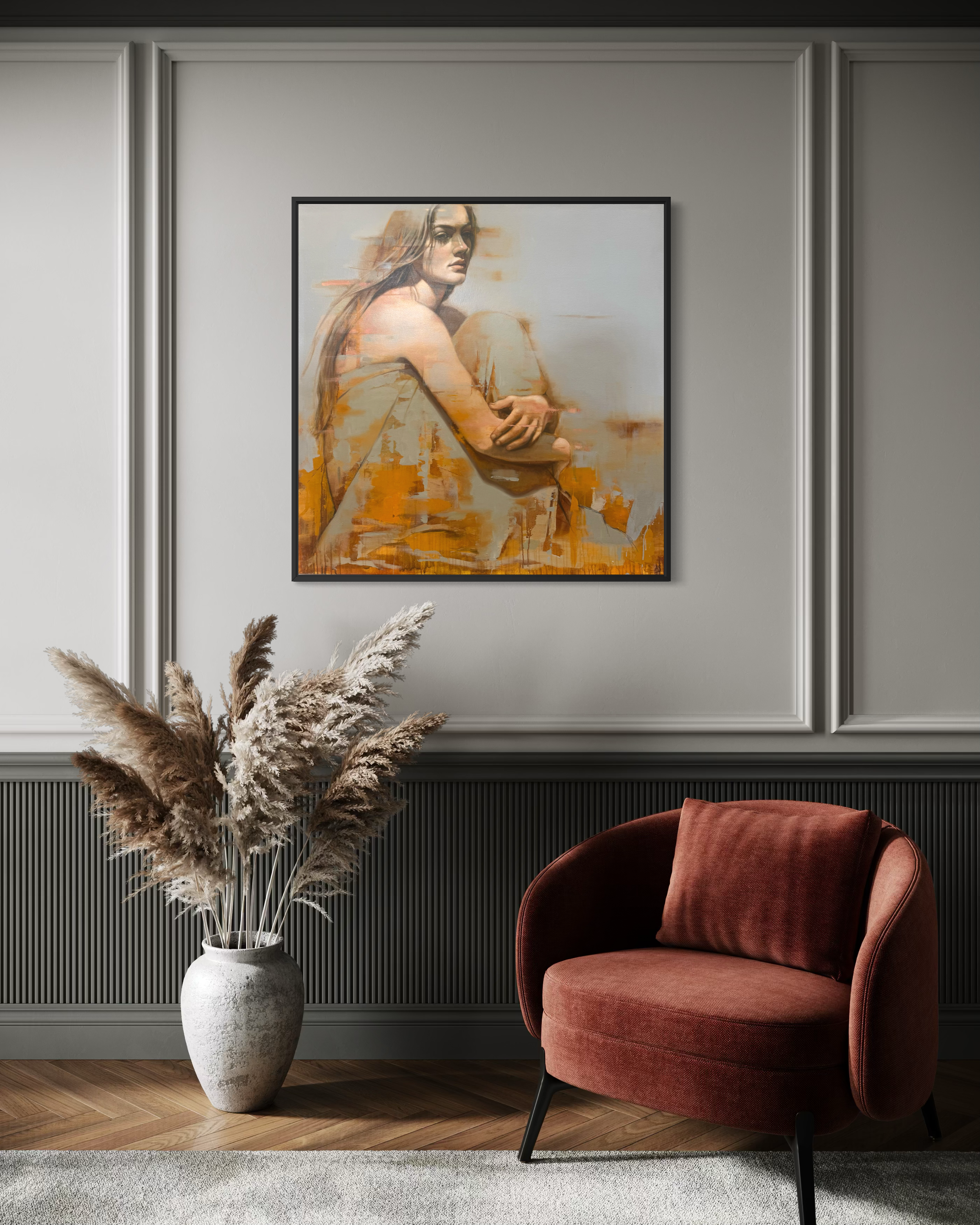 Framed abstract painting on a wall above a red armchair and decorative vase with pampas grass.