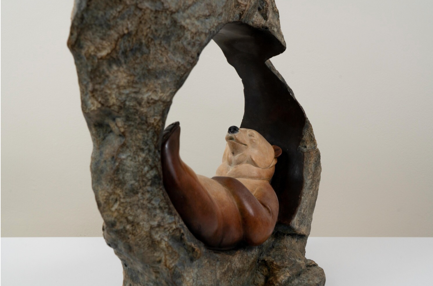 Sculpture of a bear and cub nestled together in a naturalistic setting