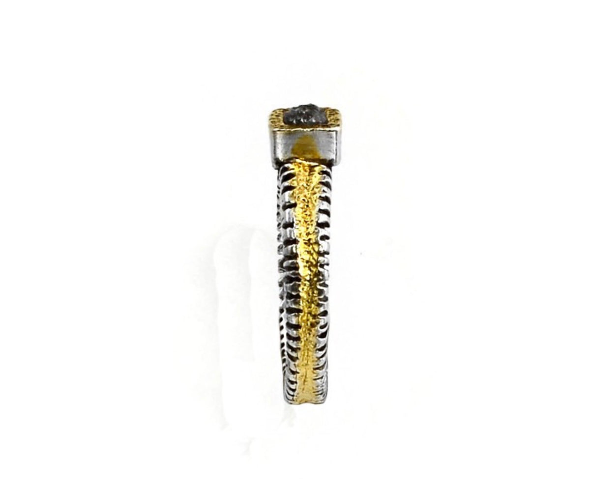 A textured two-tone ring featuring a dark gray stone in a silver bezel, with a ribbed band split between polished gold and oxidized silver.