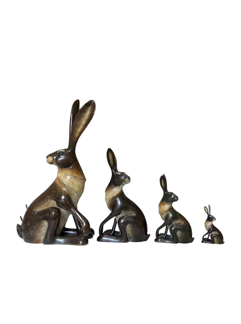 Set of four bronze rabbit sculptures on a white background