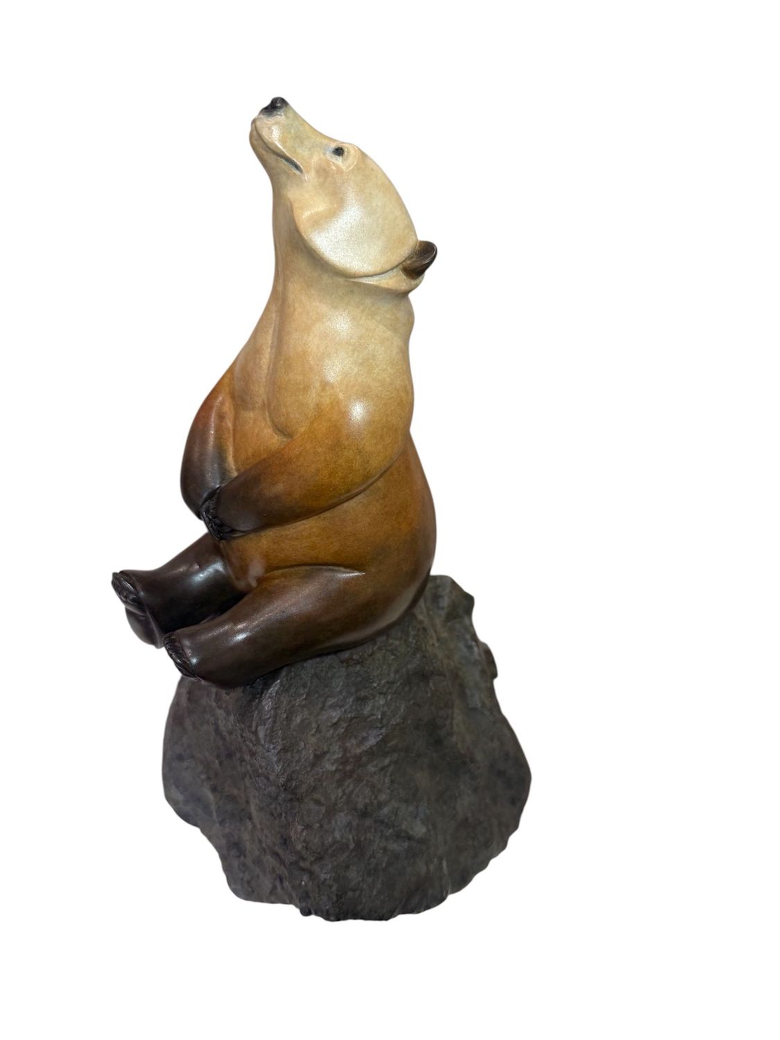 Bronze bear figurine sitting on a rock with a white background