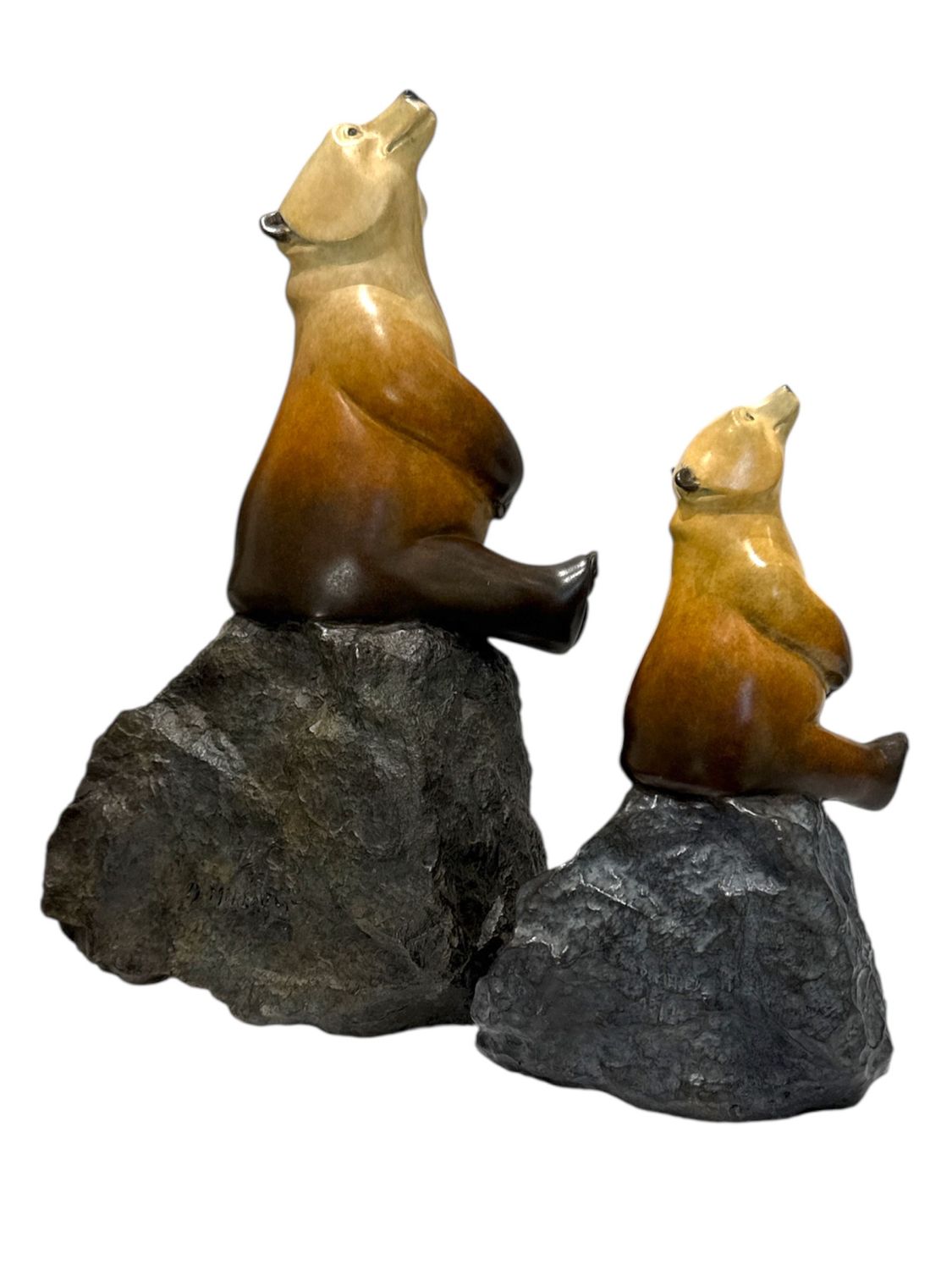 Two bear figurines sitting on rocks with a white background