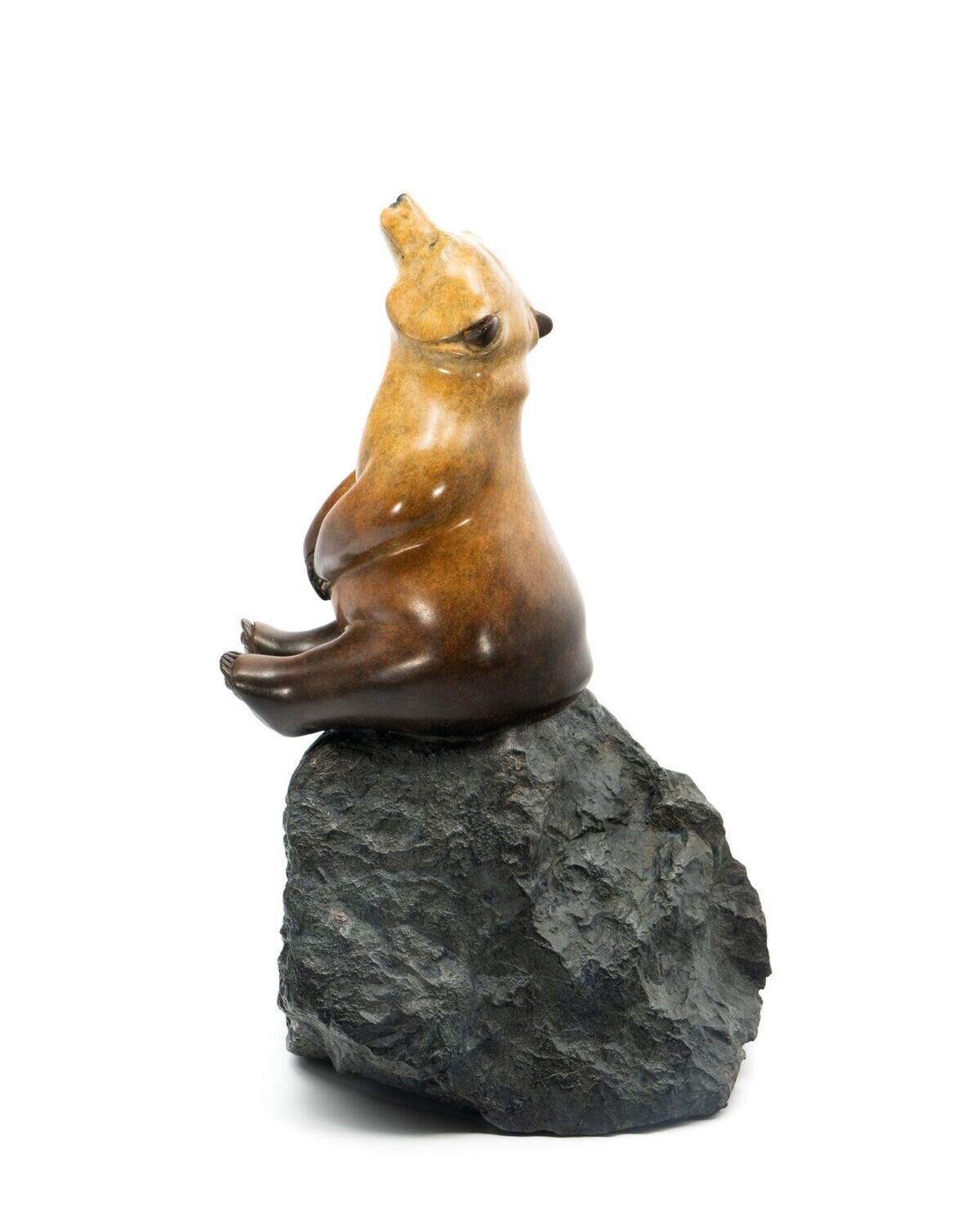 Bronze sculpture of a bear on a rock with a white background