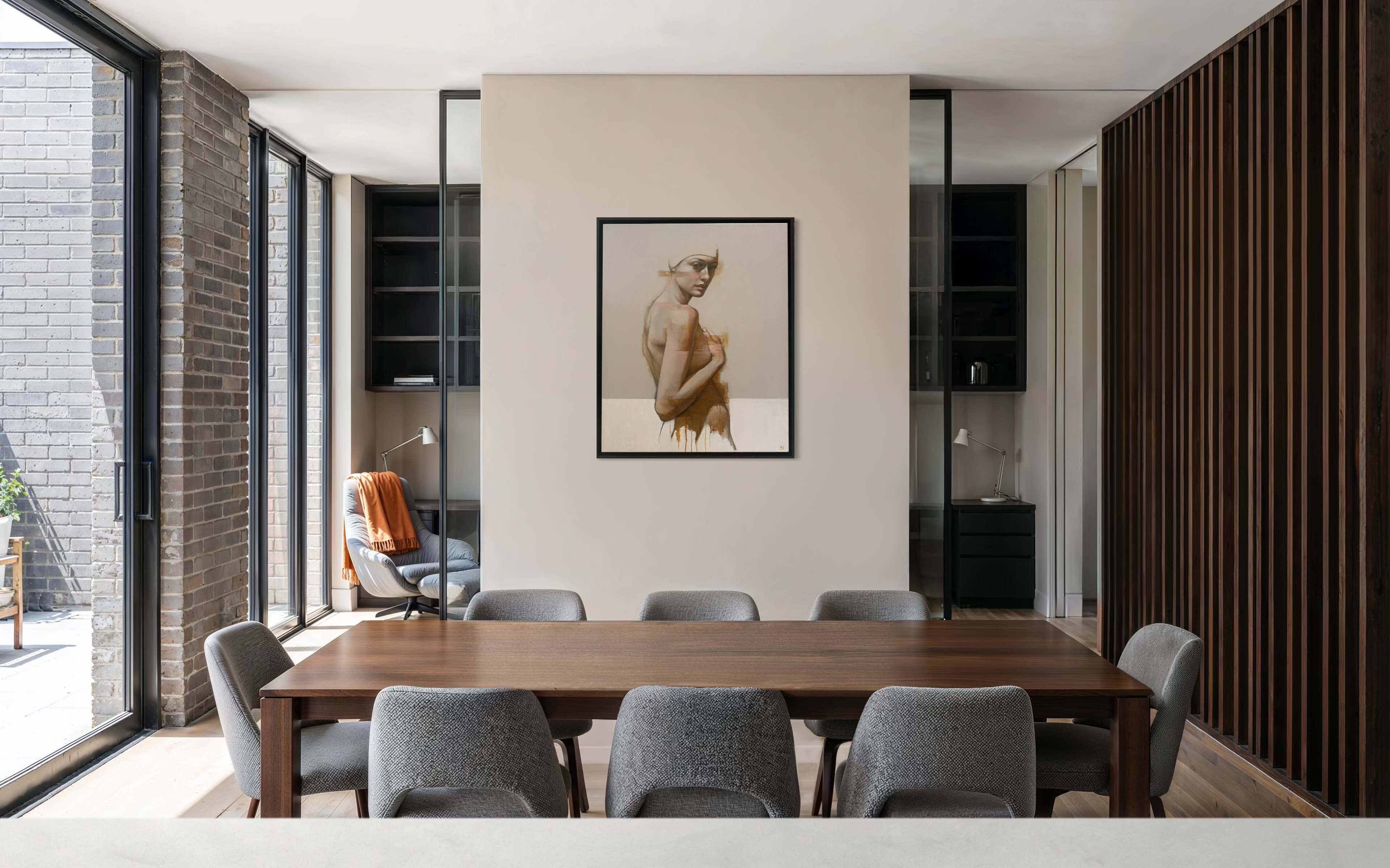 Modern dining room with wooden table and gray chairs, featuring a framed picture on the wall.