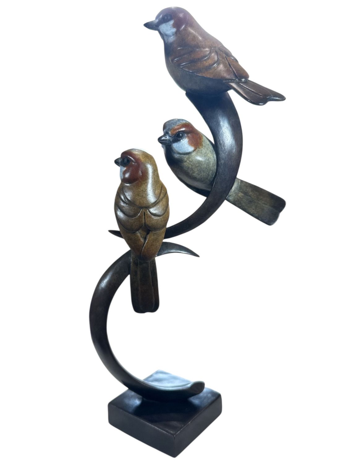 Statue of three birds perched on a curved branch on a white background