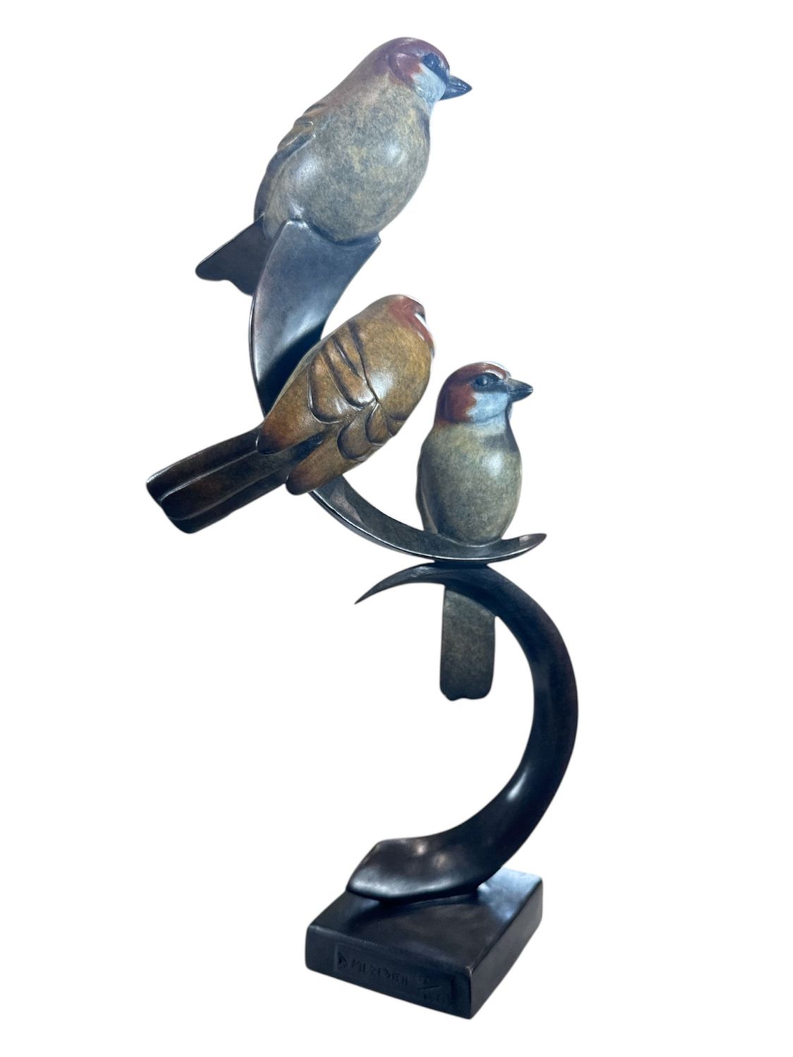 Statue of three birds perched on a curved branch with a white background