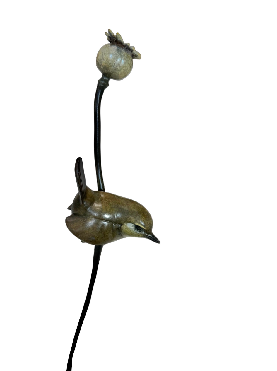 bronze sculpture of a wren perched on a poppy with a ball on top against a white background
