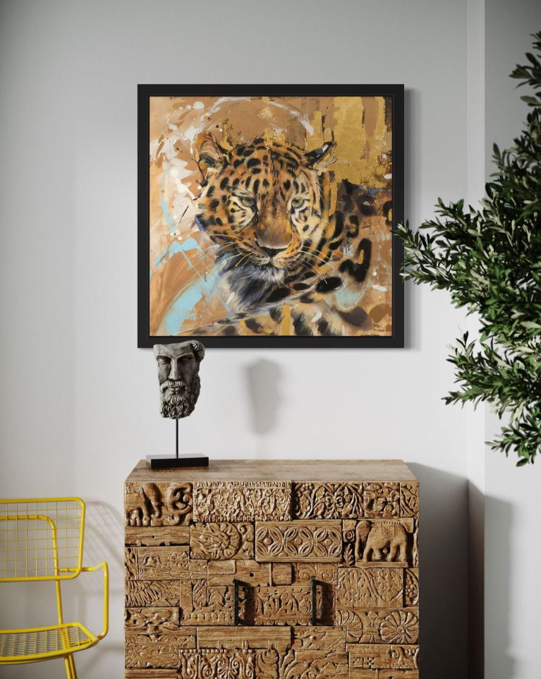 Framed artwork of a leopard on a wall above an ornate wooden chest.