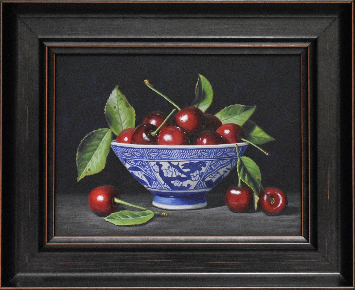 Still life painting of cherries in a blue and white bowl on a dark background