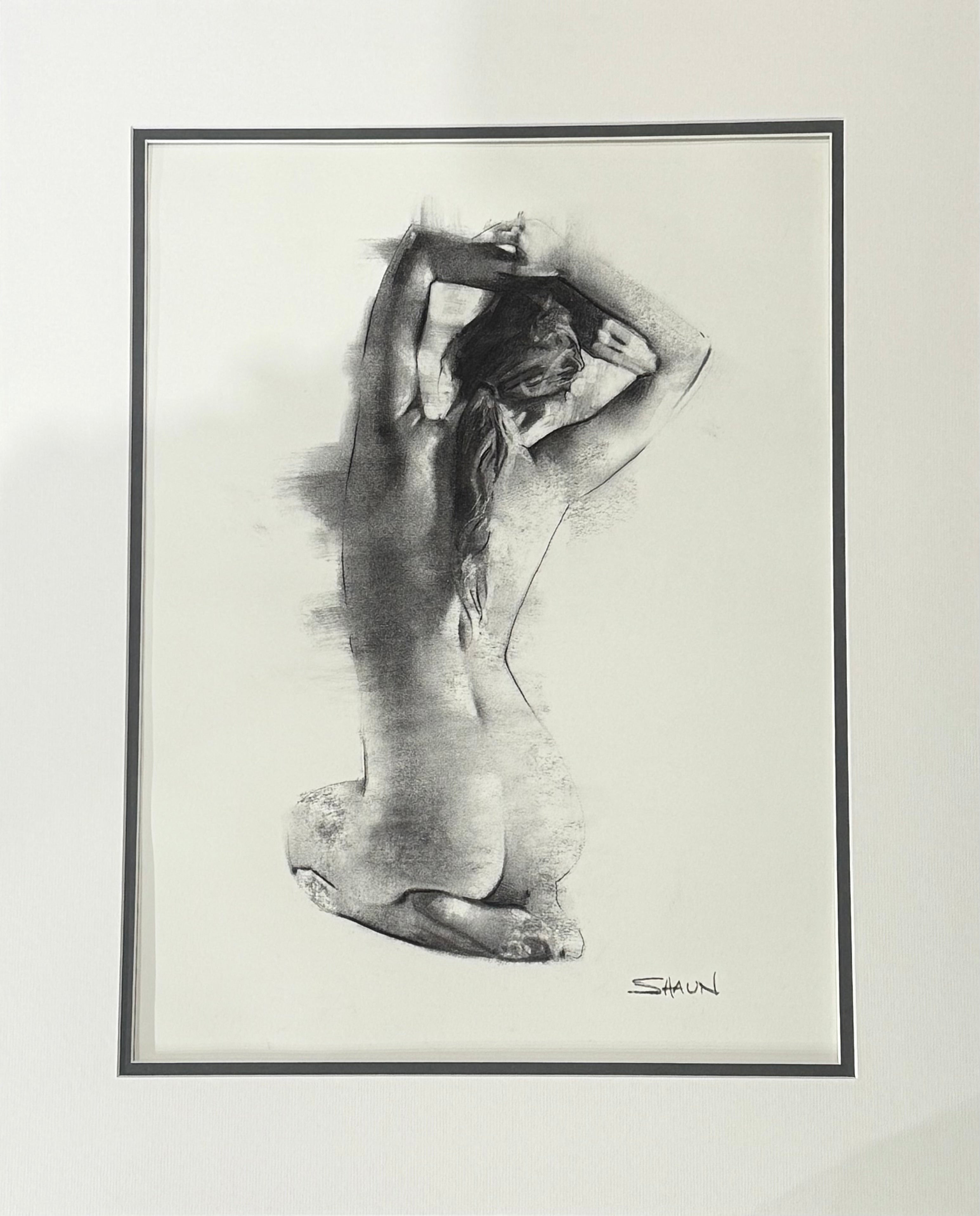 Mounted black and white artwork of a nude figure on a plain wall.
