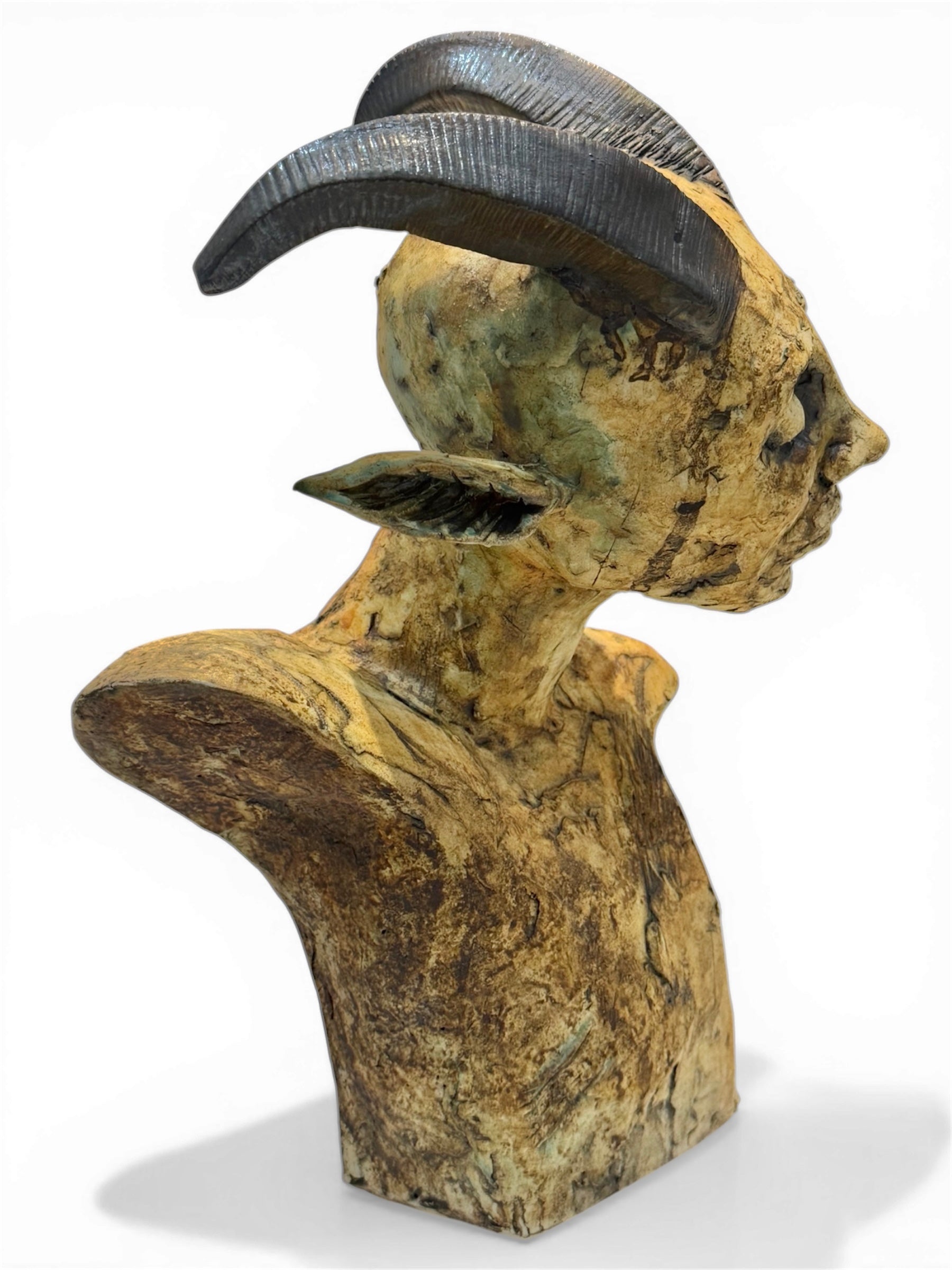 Artistic sculpture of a face with large, curved horns on a white background