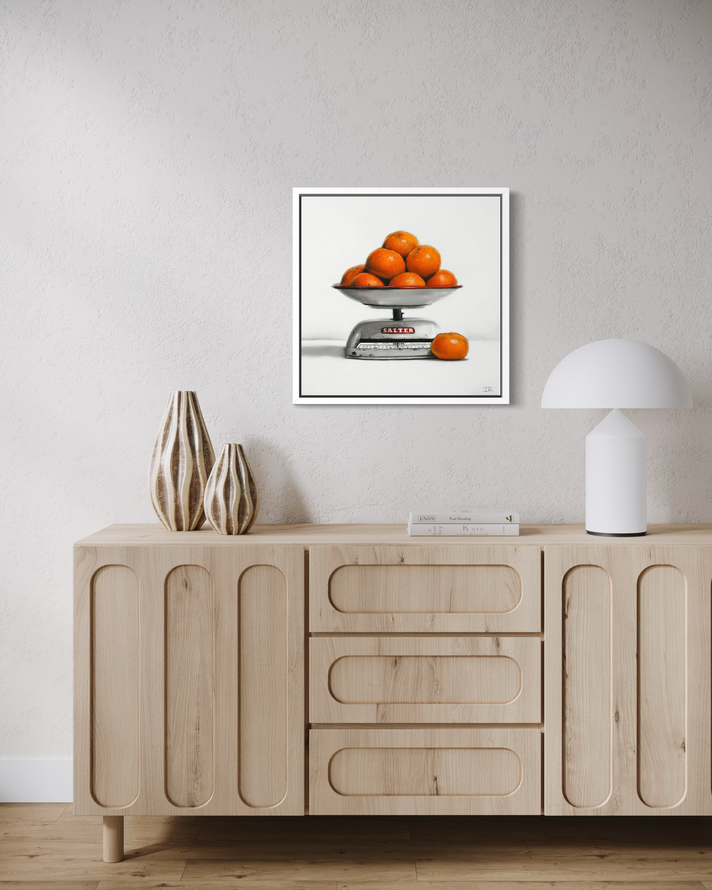 Wooden sideboard with decorative items and a framed pastel drawing of oranges on a scale.