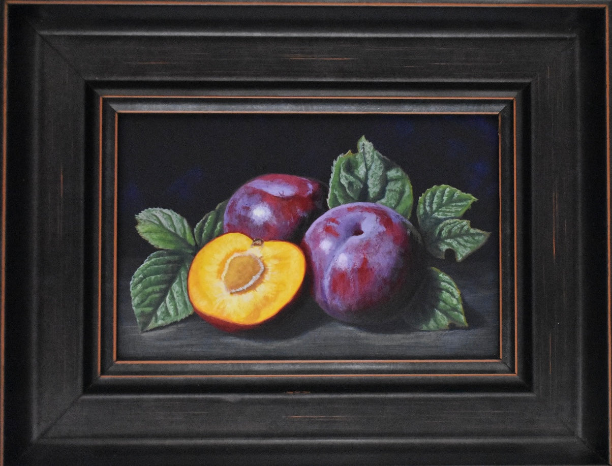 Framed still life painting of plums and an apricot with leaves on a dark background