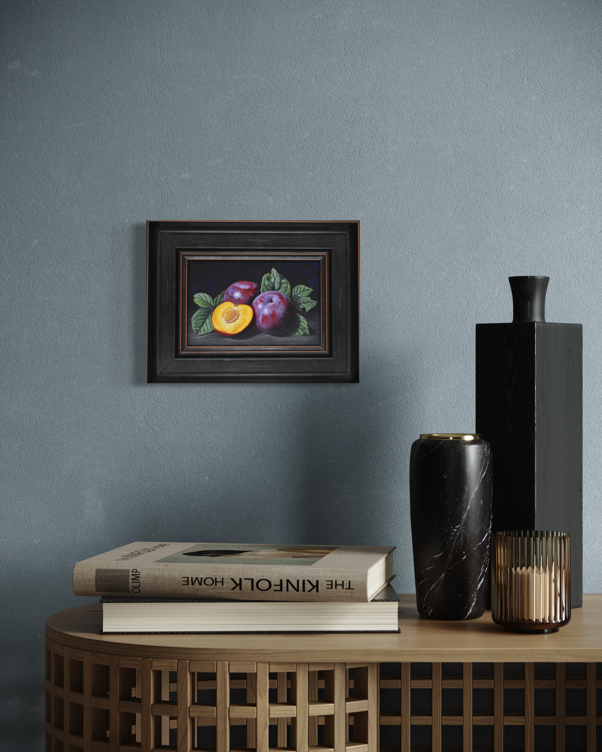 Framed still life artwork on a wall with books and vases below.