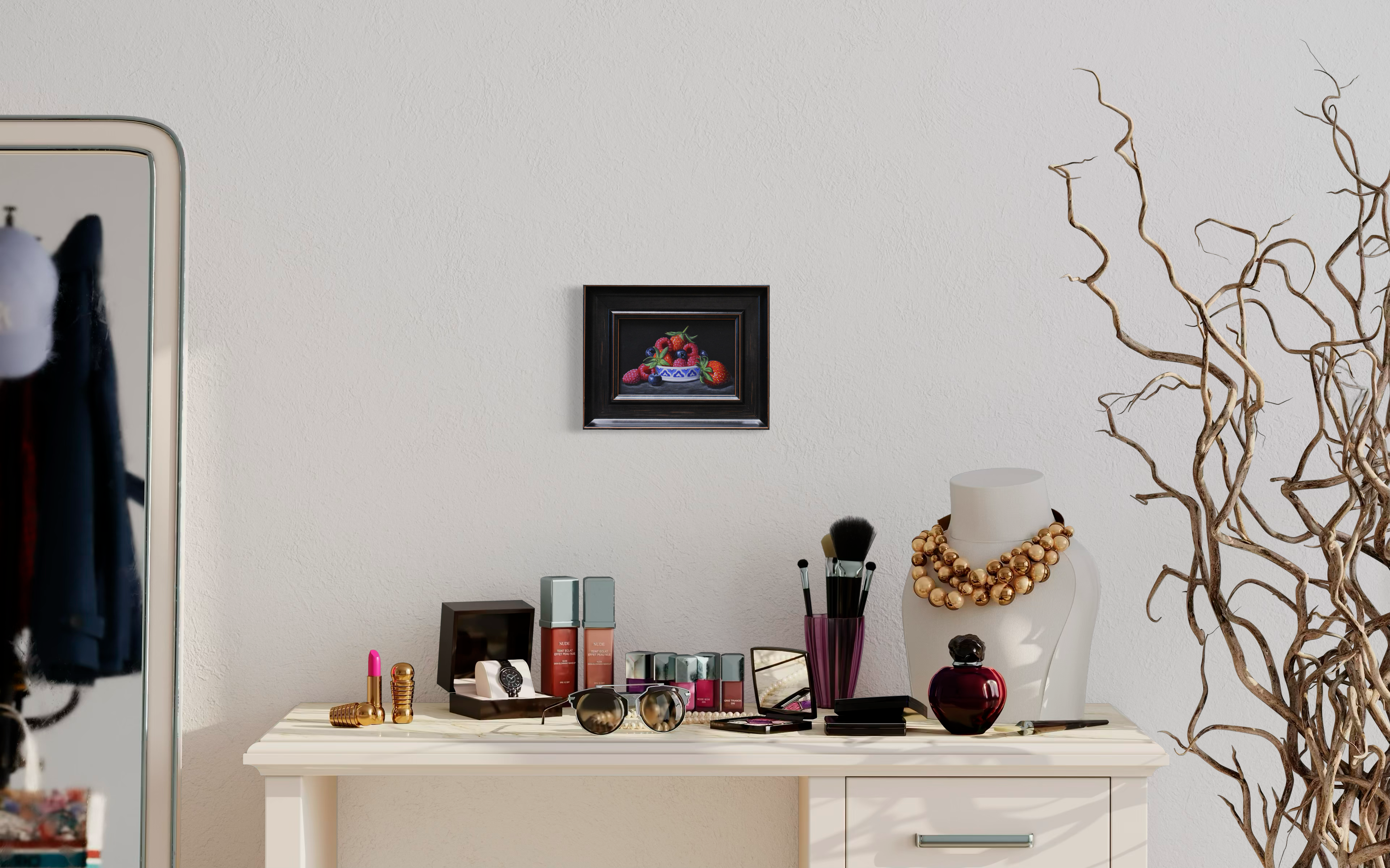 interior white vanity table with cosmetic products on top, sitting underneath a framed still life painting of berries