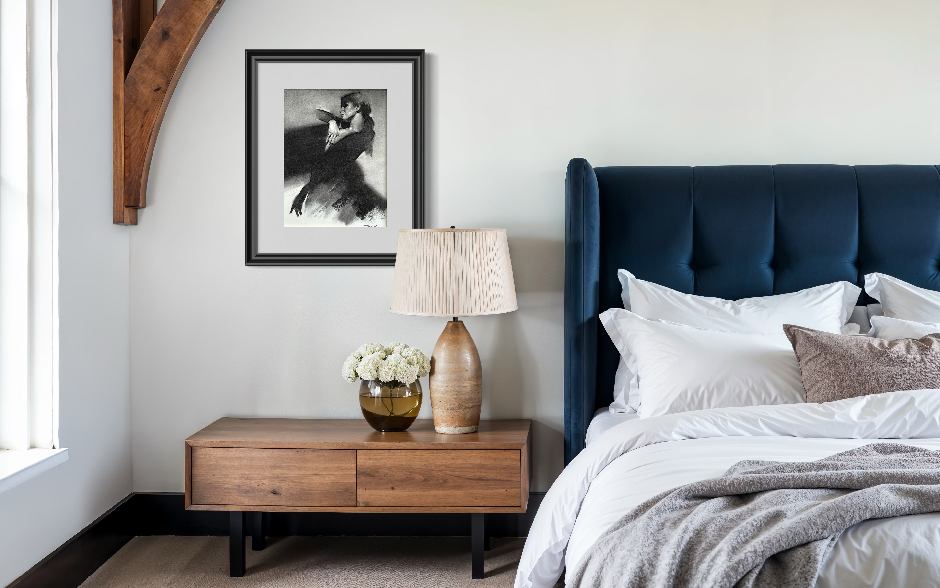 Modern bedroom with a bed, nightstand, and a framed shaun othen study hanging on the wall 