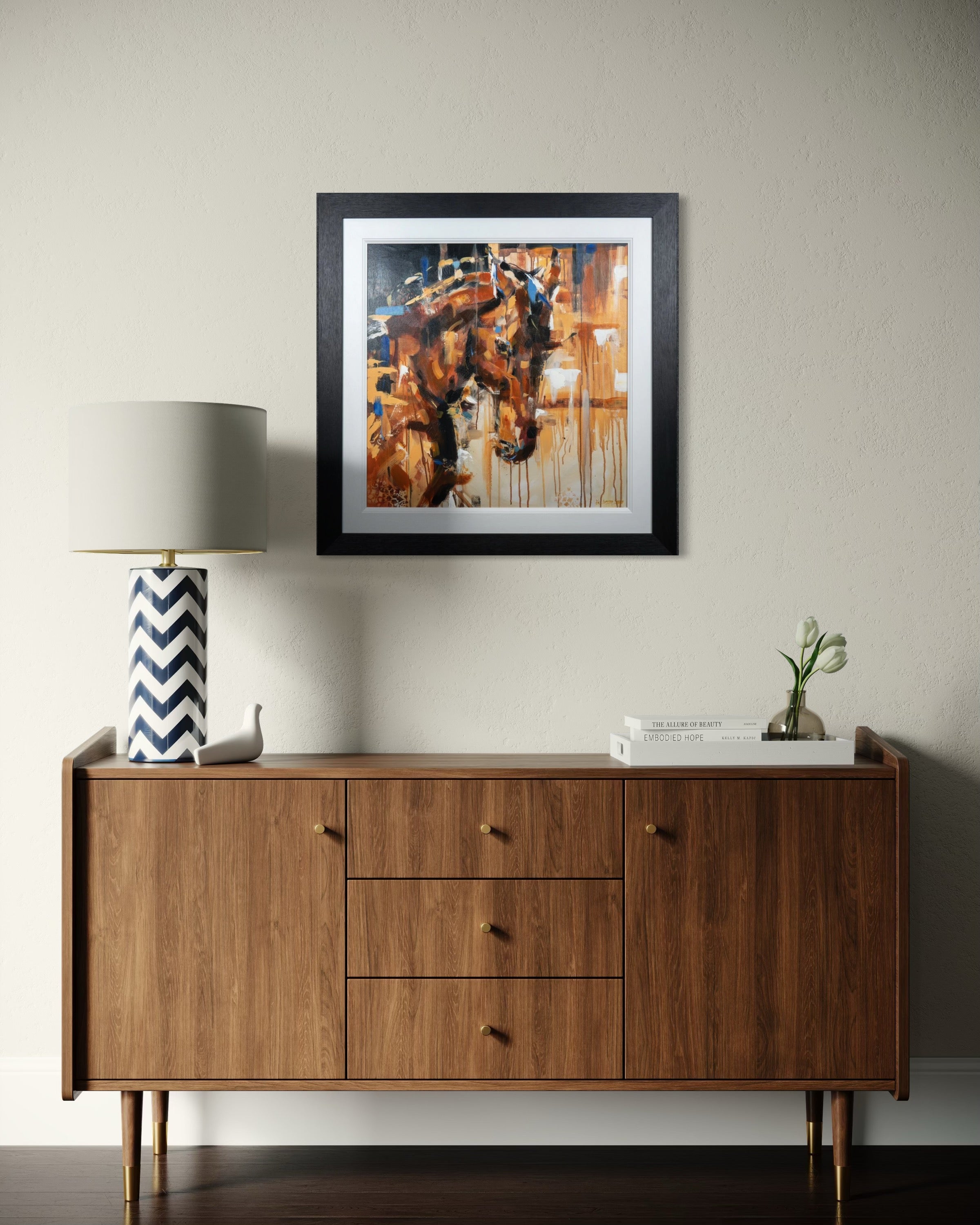 Wooden sideboard with a lamp, plant, and framed abstract art on a wall.