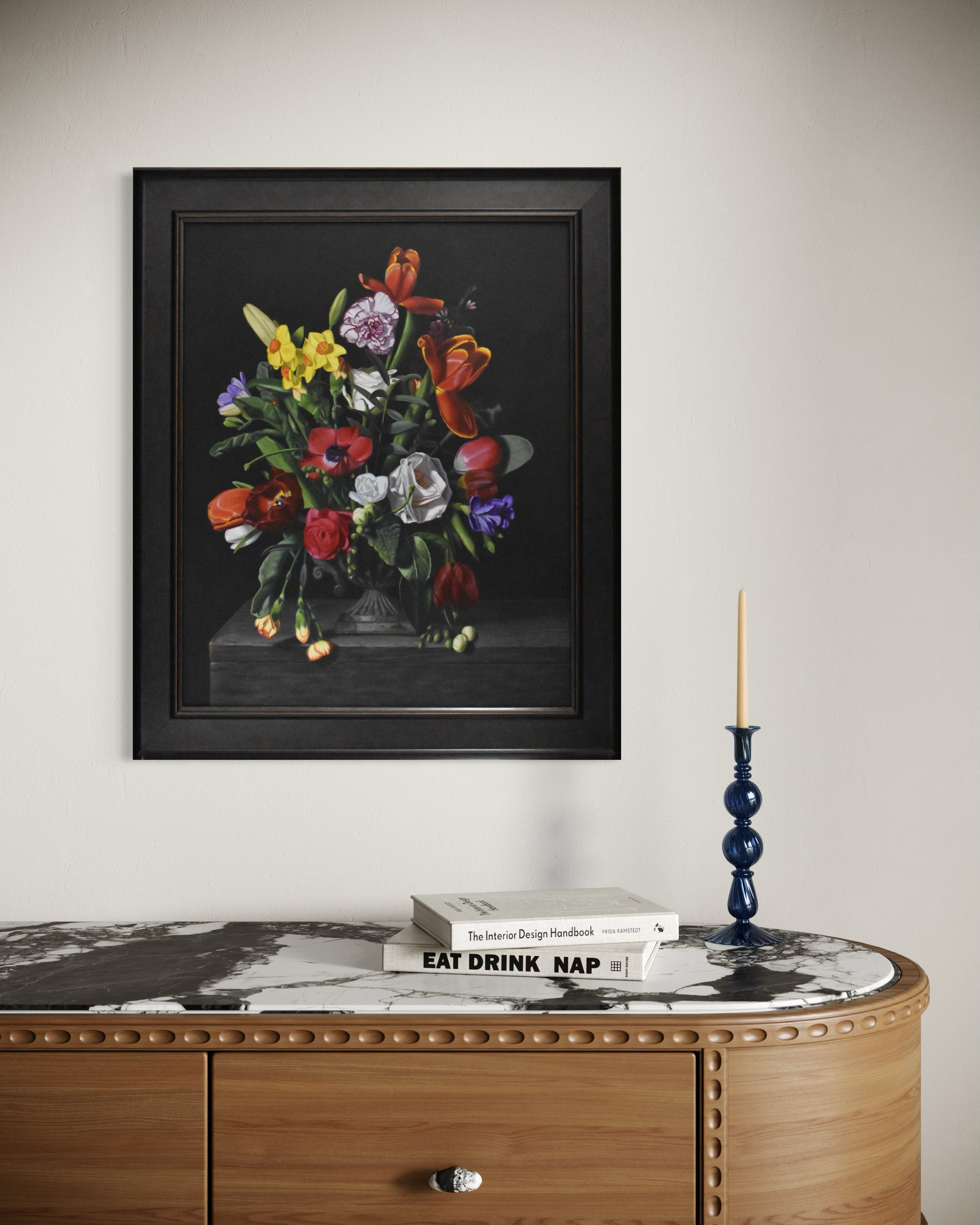 wooden consul table with marble top against a white wall with a still life painting of a bouquet of flowers hanging centrally